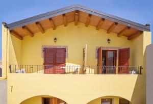 een geel huis met een balkon bij Edomat in Monserrato