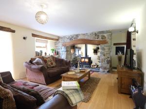 a living room with couches and a stone fireplace at Pen Y Bont in Llandwrog