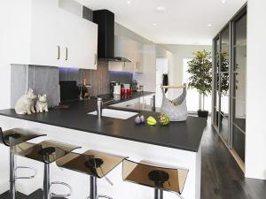 a kitchen with a black counter and stools at Quayside in Y Felinheli