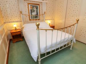 a bedroom with a white bed and two night stands at Old Codgers Cottage in Windermere