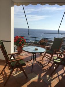 a table and chairs on a balcony with a view of the ocean at Panorama Apartments in Plomari