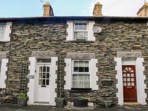 a stone house with white doors and windows at Old Codgers Cottage in Windermere