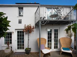 ein weißes Haus mit zwei Stühlen und einem Balkon in der Unterkunft Rhianfa Cottage in Menai Bridge + 11 Fotos