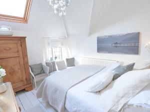 ein weißes Schlafzimmer mit einem großen Bett und einem Gemälde an der Wand in der Unterkunft Rhianfa Cottage in Menai Bridge