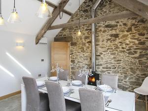 a dining room with a stone wall and a table and chairs at Rhyd Angharad Barns in Llanrhyddlad
