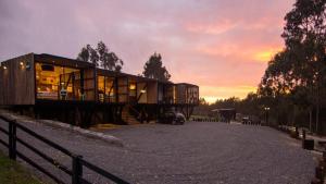 una casa en un camino de grava con una puesta de sol en el fondo en Lodge KARKÚ, en Pichilemu