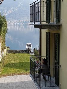 una mujer sentada en un balcón con vistas al agua en Residence Matilde, en Oliveto Lario