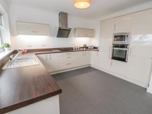 a kitchen with white cabinets and a wooden counter top at Hendre Wylan in Barmouth