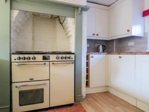 a kitchen with a stove and white cabinets at River Cottage in Tewkesbury