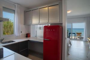 een rode koelkast in een keuken met uitzicht op de oceaan bij Sideratos Apartments in Karfás