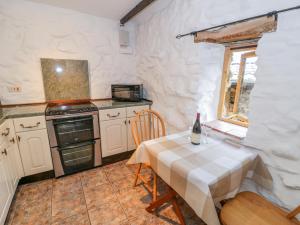 a small kitchen with a table and a stove at Waterfall Cottage in Caernarfon