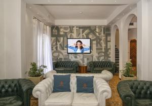 a living room with a couch and a tv on a wall at Hotel Residence Villa Marzia in Marina di Pietrasanta