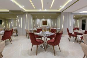 una sala da pranzo con tavoli e sedie rosse di MADAURE HOTEL a Cheraga