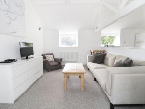 a living room with a couch and a tv and a table at Orchard Cottage in Shaftesbury