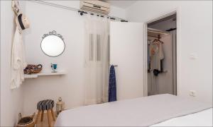 a white bedroom with a bed and a mirror at Krystalia's Apartment in Plaka Milou