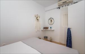 a white bedroom with a bed and a clock on the wall at Krystalia's Apartment in Plaka Milou