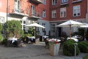 um pátio exterior com mesas e guarda-sóis em frente a um edifício em Haus Wullfcrona em Stralsund