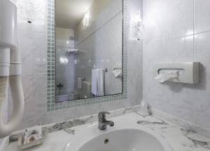 bagno bianco con lavandino e specchio di Hotel Minerva Palace a Montecatini Terme