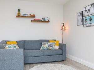 a living room with a blue couch with yellow pillows at SeaSound in Ilfracombe