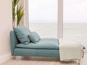 a blue couch in a room with a window at SeaSound in Ilfracombe