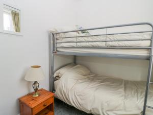 a bedroom with a bunk bed and a table with a lamp at Sea Breakers Cottage in Filey