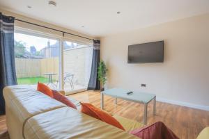a living room with a couch and a tv at Stylish Modern Newly Built Apartment 15 min From City Centre in Edinburgh +25 photos