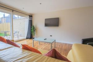 salon z kanapą i telewizorem na ścianie w obiekcie Stylish Modern Newly Built Apartment 15 min From City Centre w Edynburgu