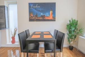 a dining room table with chairs and a painting on the wall at Stylish Modern Newly Built Apartment 15 min From City Centre in Edinburgh