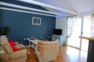 un soggiorno con pareti blu, divano e sedie di Apartman Capitano Vrsi a Vrsi (Verchè)