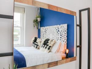 a bedroom with a blue wall and a bed with pillows at SeaSound in Ilfracombe