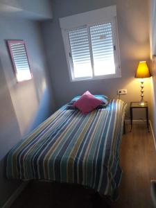 a small bedroom with a bed with a pillow and two windows at Avenue Rooms in Valencia