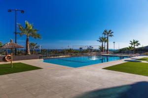 een zwembad met palmbomen en de oceaan bij Arenales Beach in Arenales del Sol