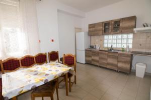a kitchen with a table and chairs and a kitchen with a refrigerator at Maria Apartman in Nyíregyháza