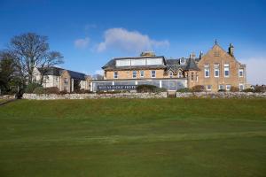 a large building on a hill with a green yard at Royal Golf Apartments in Dornoch