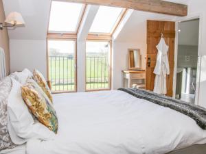 a bedroom with a large white bed with windows at Vitula Cottage in Shrewsbury