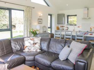 a leather couch in a living room with a kitchen at Vitula Cottage in Shrewsbury