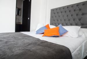 a bed with two orange and blue pillows on it at Hotel Grand H&R in Villeta
