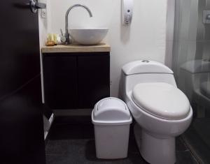 a bathroom with a white toilet and a sink at Hotel Grand H&R in Villeta
