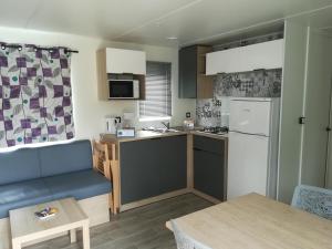 a small kitchen with a refrigerator and a table at Camping Loisirs Des Groux in Mousseaux-sur-Seine
