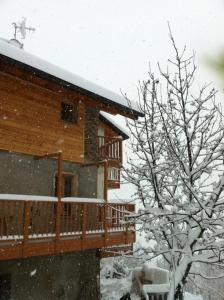 una casa in legno con una terrazza nella neve di B&B Alba Sul Lago a Pergine Valsugana