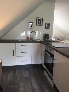 a kitchen with white cabinets and a sink at The Tree House in Inverness