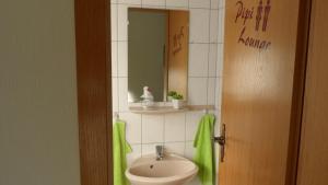 a bathroom with a sink and a mirror at Ferienhaus FRIESENNEST in Norden +10 photos