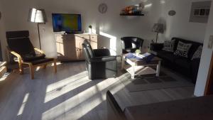 a living room with a couch and chairs and a television at Ferienhaus FRIESENNEST in Norden