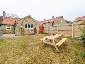 a wooden picnic table in a yard with a fence at Rose Cottage in Darlington