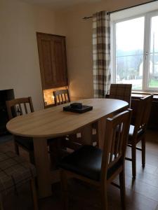a dining room table with chairs and a large window at Cliff Cottage in Kyle of Lochalsh