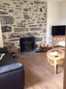 a living room with a stone wall with a fireplace at Cliff Cottage in Kyle of Lochalsh