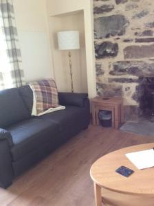 a living room with a blue couch and a table at Cliff Cottage in Kyle of Lochalsh