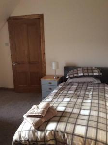 a bedroom with a bed and a dresser with a lamp at Cliff Cottage in Kyle of Lochalsh