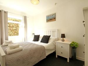 a bedroom with a white bed and a window at Swn Y Gwynt in Criccieth