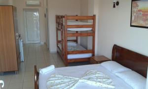 a bedroom with a bed and a bunk bed with a bow at Oasis Drymades Hotel in Dhërmi